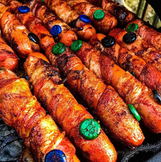 Array of hot dogs wrapped in bacon with Grill Pinz stuck within them